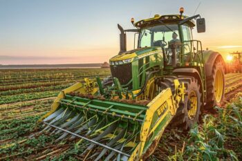 Tracteur vert dans un champ avec un coucher de soleil à l'arrière-plan